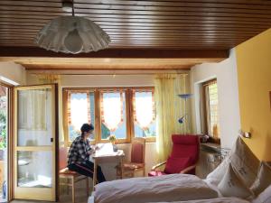 a woman sitting at a table in a bedroom at Pension Haus Rose in Oberharmersbach