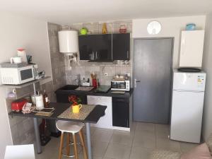 a small kitchen with a white refrigerator and a table at Studio avec jardinet clim parking in Gruissan