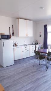 a kitchen with white cabinets and a table with chairs at Eidavellir Apartments and Rooms in Egilsstadir