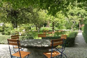 una mesa y sillas en un jardín con árboles en Hotel Palazzo Salis en Soglio