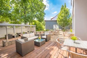 eine Terrasse mit Tischen und Stühlen auf einer Holzterrasse in der Unterkunft Hotel Am Kurpark Späth in Bad Windsheim