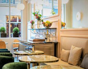 un ristorante con due tavoli, sedie e finestre di Hôtel Veryste & Spa Paris a Parigi
