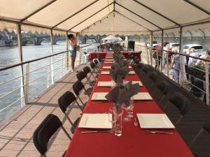 a long table on a boat with red tables and chairs at La Valse Lente in Namur