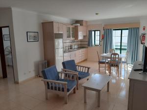 a kitchen and living room with blue chairs and a table at Dunas 107 in Alvor