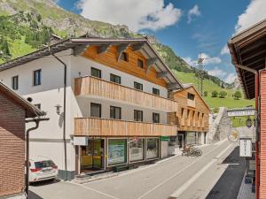 un bâtiment dans une rue avec des montagnes en arrière-plan dans l'établissement Haus Flexen, à Stuben am Arlberg