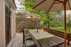 a table and an umbrella on a patio at Biserka apartments near the beach and center in Mali Lošinj