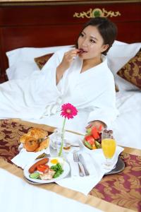 Eine Frau, die mit einem Tablett Essen im Bett liegt. in der Unterkunft Royal House Hotel in Ulaanbaatar