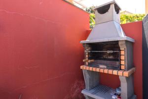 a brick oven sitting next to a red wall at Casa das Camélias in Arco da Calheta