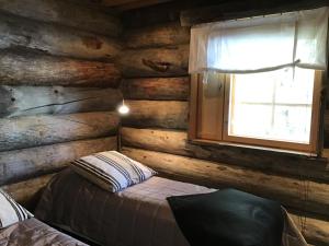a log cabin bedroom with a bed and a window at Rukan Villa Nuotta in Ruka