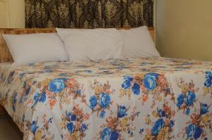 a bed with a floral comforter with two pillows at Hotel Ambassadors in Lomé