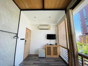 a room with a balcony with a television and a door at Vann Bangkok Boutique House in Bangkok