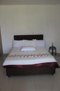 uma cama com lençóis brancos e almofadas num quarto em Salient Guest House em Eldoret