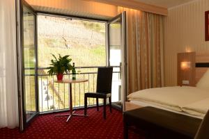 a hotel room with a bed and a table and a balcony at Strandhaus an der Mosel in Valwig