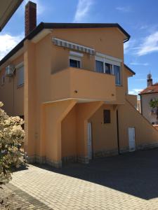une grande maison jaune dans une allée en briques dans l'établissement Apartmani Dekovic Materada, à Poreč