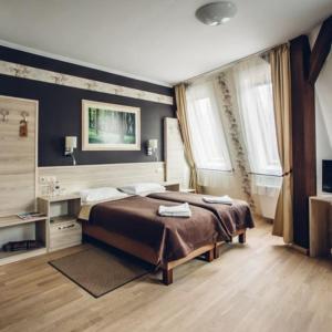 a bedroom with a large bed and two windows at Natur Hotel Kövestető in Hosszúhétény-Szőlőhegy