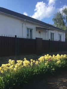 a white house with a fence and yellow flowers at Апартаменты в центре с парковкой in Cherkasy
