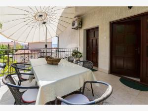 a table and chairs with an umbrella on a balcony at Apartments Dora in Selce