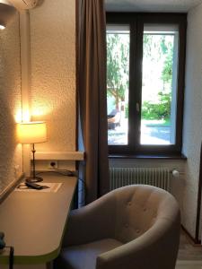 a room with a desk and a chair and a window at Les Tilleuls Montbeliard Sud Audincourt in Audincourt