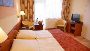 ティメンドルファー・シュトラントにあるAura Hotelのベッドとテレビが備わるホテルルームです。