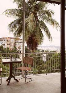 a table and chair on a balcony with a palm tree at Mama Ruisa Boutique Hotel in Rio de Janeiro