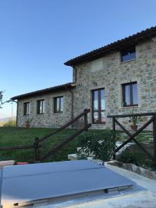 una casa de piedra con una valla de madera delante de ella en Agriturismo Sant'Angelo holiday farm, en Gualdo Cattaneo
