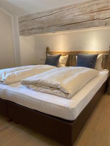 a large bed with white sheets and blue pillows at Zum Schweizerbartl in Garmisch-Partenkirchen