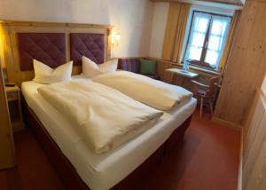 1 dormitorio con 1 cama grande con sábanas blancas en Zum Schweizerbartl, en Garmisch-Partenkirchen