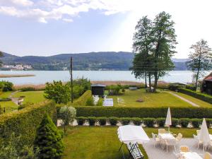 a garden with tables and chairs and a lake at A Part of Eden in Krumpendorf am Wörthersee