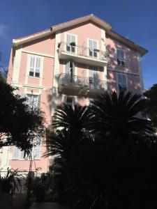 un edificio rosa con palmeras delante en Hotel Lucciola en Bordighera