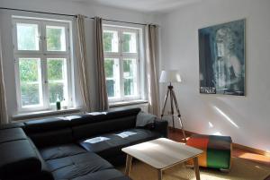 een woonkamer met een zwarte bank en 2 ramen bij Jasmundhus in Neddesitz