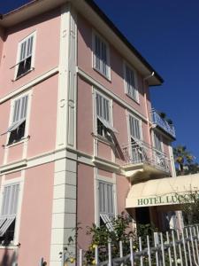 un hotel rosa con una valla delante en Hotel Lucciola en Bordighera
