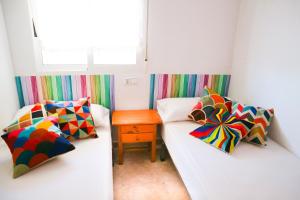 Habitación pequeña con 2 camas y almohadas coloridas. en Gavina Azul, en Villajoyosa