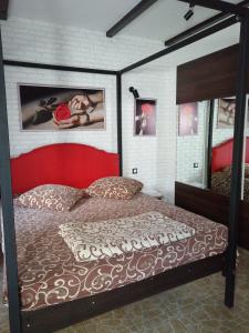 a bedroom with a large bed with a red headboard at Hotel Vivat in Velikodolinskoye