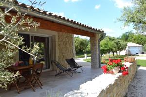 un patio con sillas, una mesa y flores en La Romagnolette, en Saint-Restitut