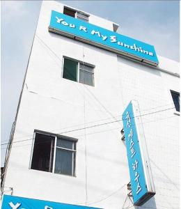 a white building with a blue sign on it at Yusun Guesthouse in Busan