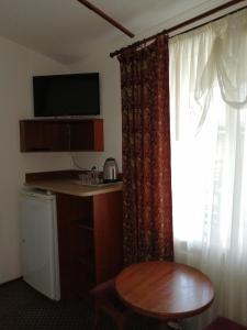 a room with a table and a window with a table and a small table sidx at Hotel Vivat in Velikodolinskoye