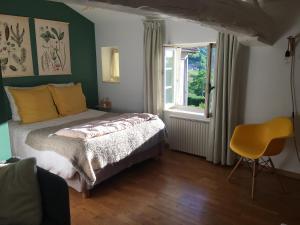 um quarto com uma cama, uma janela e uma cadeira em Les Picorettes em Vaux-en-Beaujolais