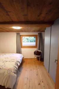 una camera con letto, finestra e sedia di Ferienhaus Z‘ Gädi a Ernen