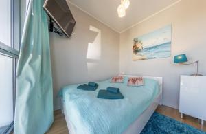 a bedroom with a bed with blue sheets and a tv at Horyzont by Baltic Home in Międzyzdroje