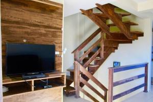 a living room with a tv and a wooden staircase at LINDO SOBRADO A 250mts DA PRAIA MARISCAL PISCINA 249-3 in Bombinhas