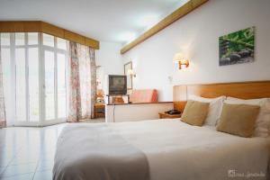 a bedroom with a large white bed and a television at Pantanha Apartment by Trip2Portugal in Nelas