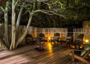 a deck with chairs and a table and a tree at APS Guesthouse in Windhoek