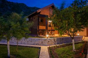 a log cabin with a stone wall and trees at Ethno Lodge AB in Virpazar