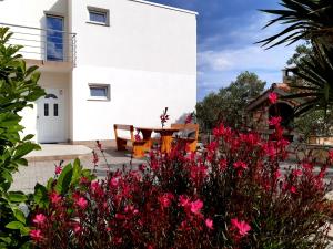 Apartments AS في يزيرا: منزل أبيض مع طاولة وورود وردية