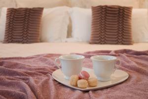 dos tazas y un plato con galletas en una cama en Accanto Al Centro B&B, en Prato