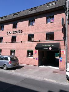 a brick building with a car parked in front of it at Lys Hôtel in Halluin