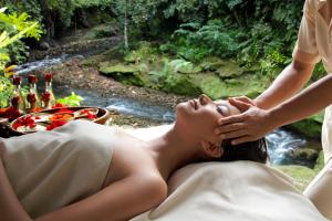 een vrouw die op een bed ligt en een massage krijgt bij Hotel Tjampuhan Spa in Ubud
