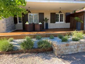 um alpendre frontal de uma casa com algumas plantas em Chambre d'hôtes de la Riaille 400 m de la dolce via em Le Cheylard