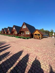 a row of log cabins with their shadows on the ground at Komfortowe Domki Dar in Sianozety