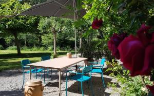 - une table et des chaises avec un parasol dans le jardin dans l'&eacute;tablissement Moulin Renaudiots - Maison d'h&ocirc;tes, &agrave; Autun